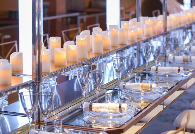 Pusty zestaw naczyń i świece w restauracji z długim stołem