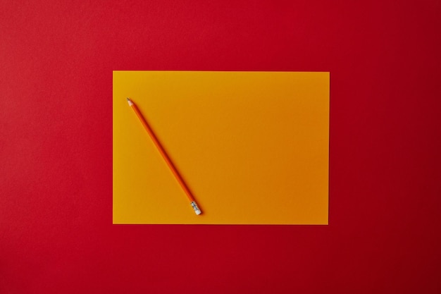 Zdjęcie pusty żółty papier z czerwonym barwionym ołówkiem odizolowywającym na czerwonym tle.