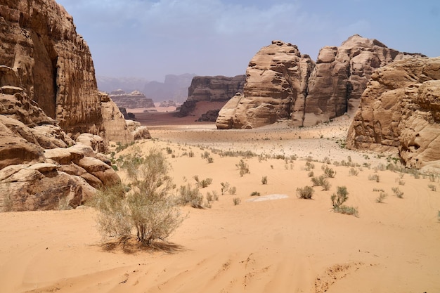 Pustynia Wadi Rum Jordania Bliski Wschód Dolina Księżyca Pomarańczowy piasek zamglenie chmury Wpisanie na Listę Światowego Dziedzictwa UNESCO Park Narodowy na zewnątrz krajobraz Przygody terenowe tło podróży