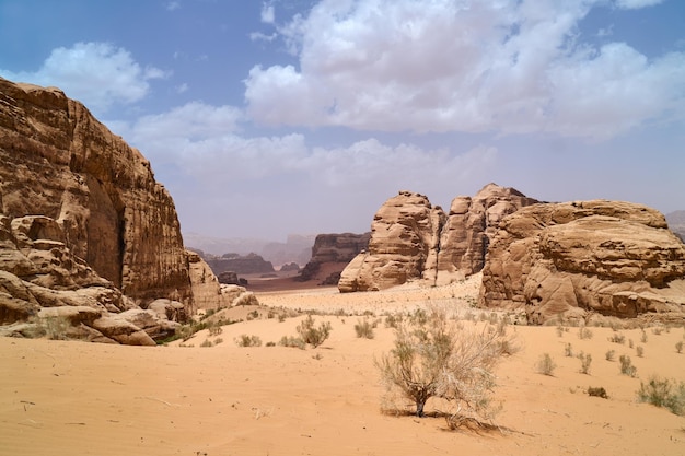 Pustynia Wadi Rum Jordania Bliski Wschód Dolina Księżyca Pomarańczowy piasek zamglenie chmury Wpisanie na Listę Światowego Dziedzictwa UNESCO Park Narodowy na zewnątrz krajobraz Przygody terenowe tło podróży