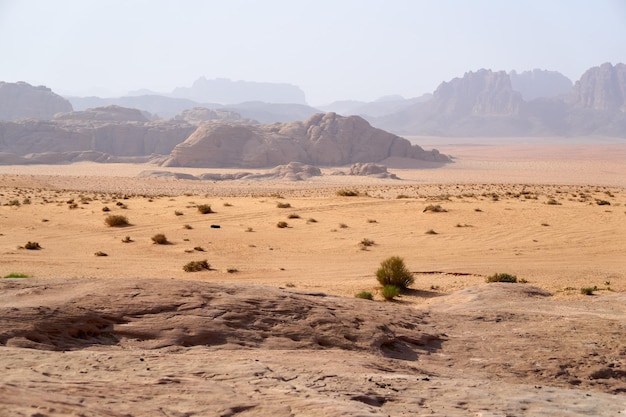 Pustynia Wadi Rum Jordania Bliski Wschód Dolina Księżyca Pomarańczowy piasek zamglenie chmury Wpisanie na Listę Światowego Dziedzictwa UNESCO Park Narodowy na zewnątrz krajobraz Przygody terenowe tło podróży