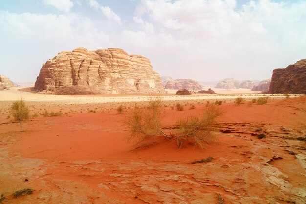 Pustynia Wadi Rum Jordania Bliski Wschód znana jako Dolina Księżyca Pomarańczowy piasek Błękitne niebo zamglenie i chmury Wpisanie na Listę Światowego Dziedzictwa UNESCO Czerwona planeta Krajobraz Marsa