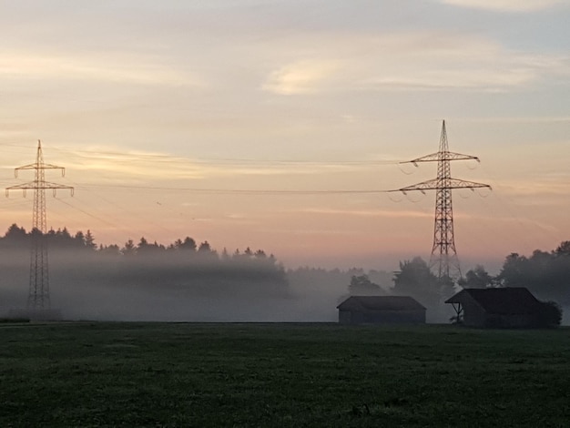 Zdjęcie pylon elektryczny na polu przeciwko niebu podczas zachodu słońca