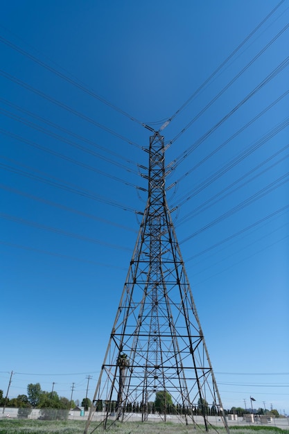 Pylon wytwarzający transmisję napięcia energetycznego na wieży elektrycznej potężna podstacja wysokiego napięcia na tle błękitnego nieba bez tła miejskiego linie elektroenergetyczne