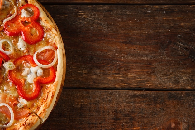 Pyszna apetyczna kolorowa pizza serwowana na rustykalnym drewnianym stole z wolnym miejscem na tekst. Włoskie tradycyjne fast foody tło, leżał płasko.