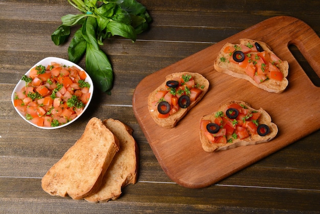 Zdjęcie pyszna bruschetta z pomidorami na zbliżenie deski do krojenia