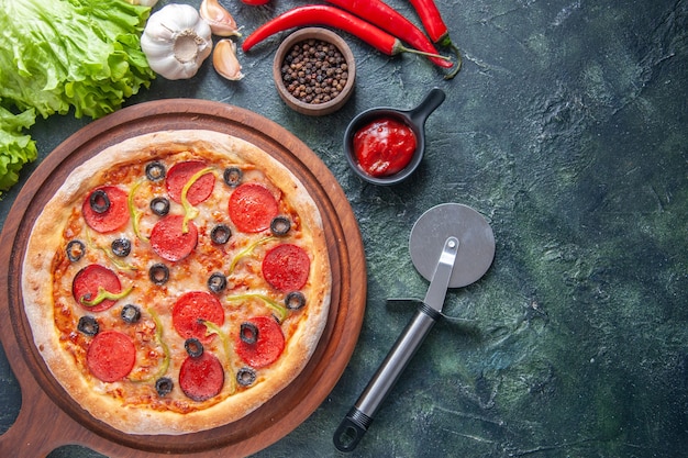 Pyszna domowa pizza na drewnianej desce pomidory ketchup czosnek pieprz olej butelka zielony pakiet po prawej stronie na ciemnej powierzchni