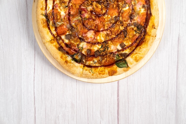 Pyszna duża pizza z bekonem i szpinakiem na jasnym drewnianym tle