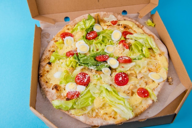 Pyszna gorąca pizza w kartonowym pudełku na jasnoniebieskim tle Selektywne skupienie