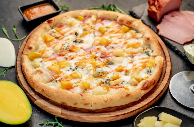 pyszna pizza z szynką ser ananas mango na kamiennym tle