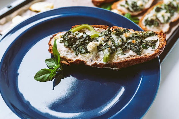 Pyszna świeża bruschetta z pieczarkami, szpinakiem, serem, twarogiem i papryką, na talerzu.