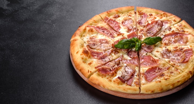 Pyszna świeża chrupiąca pizza z pieca z szynką, serem i bazylią. Kuchnia włoska