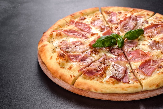 Zdjęcie pyszna świeża chrupiąca pizza z pieca z szynką, serem i bazylią. kuchnia włoska