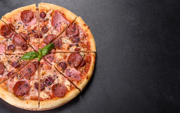 Pyszna świeża pizza z pieca z pomidorami, salami i boczkiem na ciemnym tle betonu. Kuchnia włoska