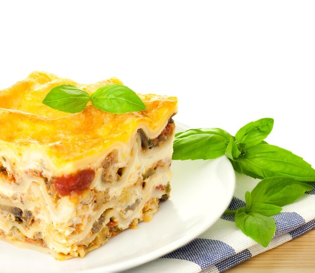 Pyszna włoska lasagne ze świeżą bazylią na białym tle i kopią spase