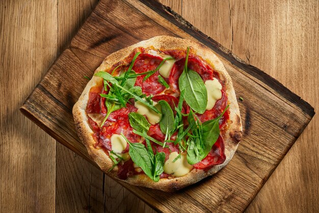 Pyszna włoska pizza z chrupiącymi dodatkami nadziewana włoskim chorizo, topionym serem i czerwonym sosem. pizza na stole z drewna