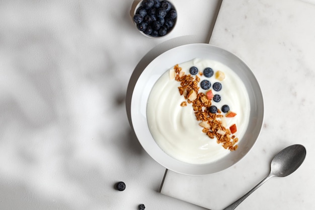 Pyszna, zdrowa miska śniadaniowa z białym jogurtem, świeżymi jagodami z musli lub musli Widok z góry