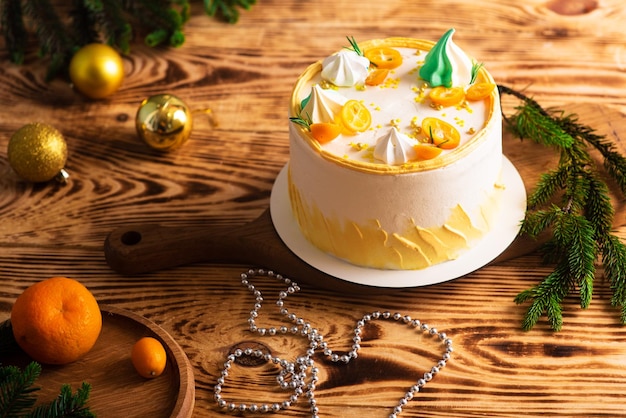 Pyszne białe ciasto z pomarańczowymi i świerkowymi gałązkami na drewnianej, przetartej, świątecznej dekoracji atmosferyczne zdjęcie