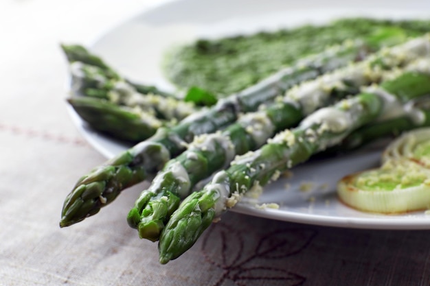 Zdjęcie pyszne danie ze szparagów z cebulą i zielonym sosem na stole z bliska