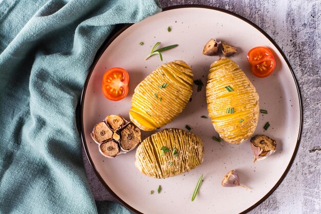 Pyszne domowe pieczone ziemniaki hasselback z czosnkiem i rozmarynem na talerzu Widok z góry Zbliżenie