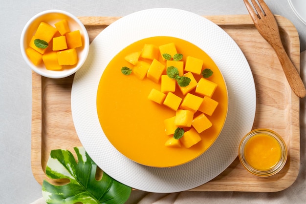 Pyszne glazurowane mango bez pieczonego sernika ze świeżą pokrojoną w kostkę miazgą z mango na jasnym tle stołu