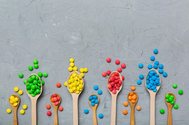 Pyszne kolorowe słodkie cukierki na łyżce na kolorowym tle Wystrój cukierniczy widok z góry z miejsca na kopię