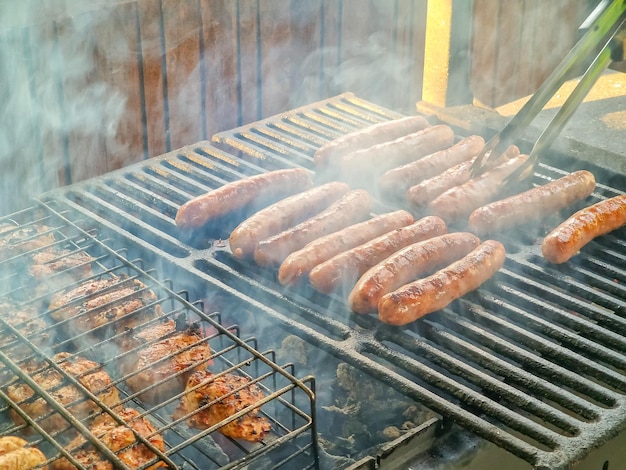 Pyszne niemieckie kiełbaski skwierczące nad węglami na grillu grillman gotuje mięso na grillu gril