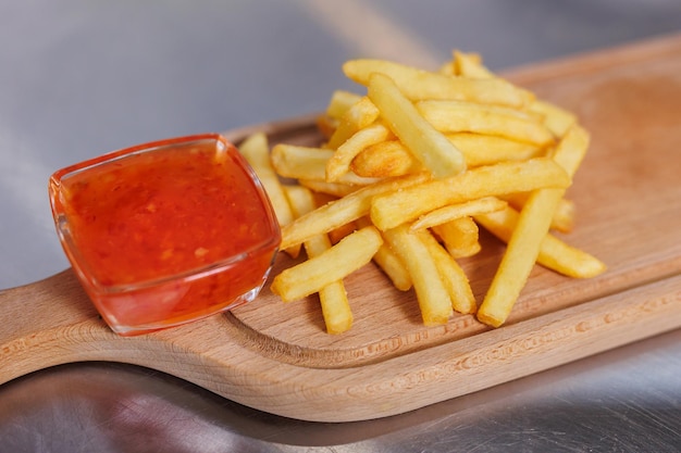 Pyszne smażone frytki z sosem na drewnianej desce Gorące fast food