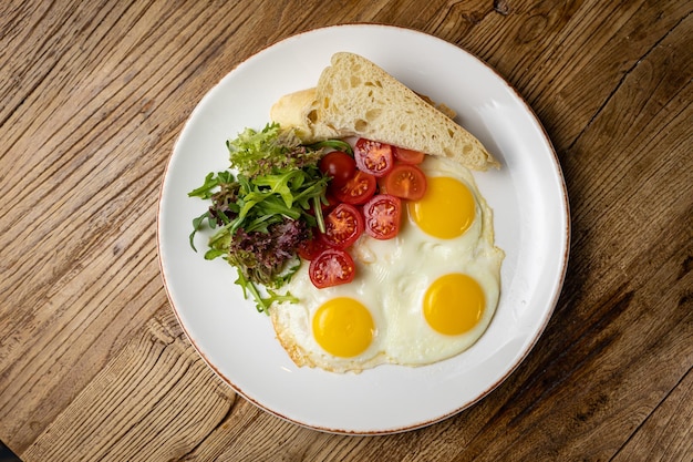 pyszne śniadanie na talerzu przygotowane w restauracji. Jajka sadzone z pomidorami i sałatką