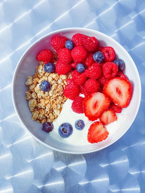 Pyszne śniadanie z jogurtem zbożowym, truskawkami malinami i jagodami w ogrodzie na świeżym powietrzu zdrowa żywność i dieta