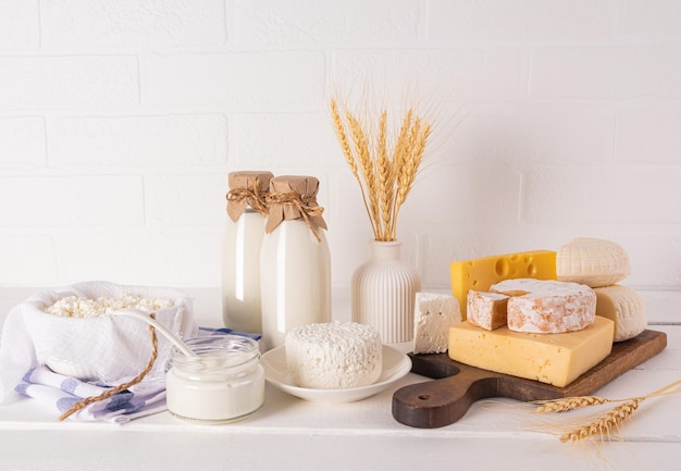 Pyszne świeże produkty mleczne na Shavuot na drewnianej desce do cięcia i białym stole wazon z kukurydzą Koncepcja żydowskiego święta