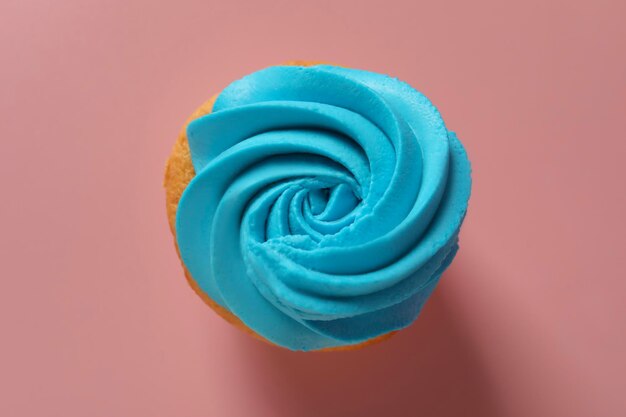 Pyszny cupcake z jasnym kremem na różowym tle widok z góry