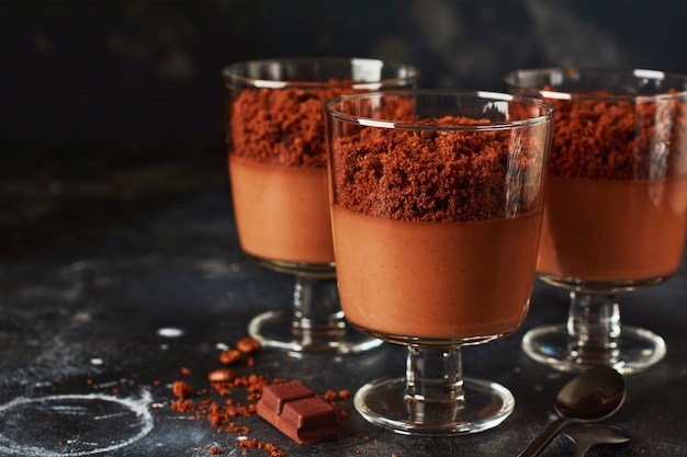 Zdjęcie pyszny deserowy mus czekoladowy z brownie w szklanych słoikach na jasnym tle łupkowym, kamiennym lub betonowym. selektywna ostrość.