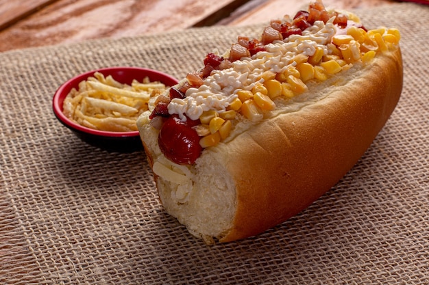 Pyszny hot dog z dodatkami i na kolorowym lub drewnianym tle