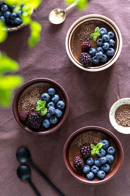 Pyszny mus czekoladowy lub panna cotta z jagodami i jagodami na ciemnym tle tkaniny Vertical