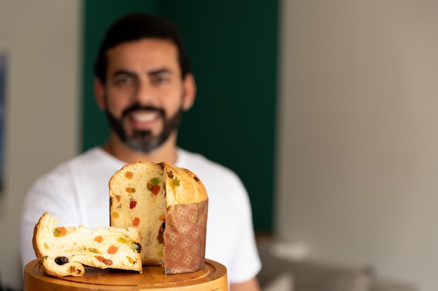 pyszny świąteczny panettone serwowany przez uśmiechniętego mężczyznę w tle