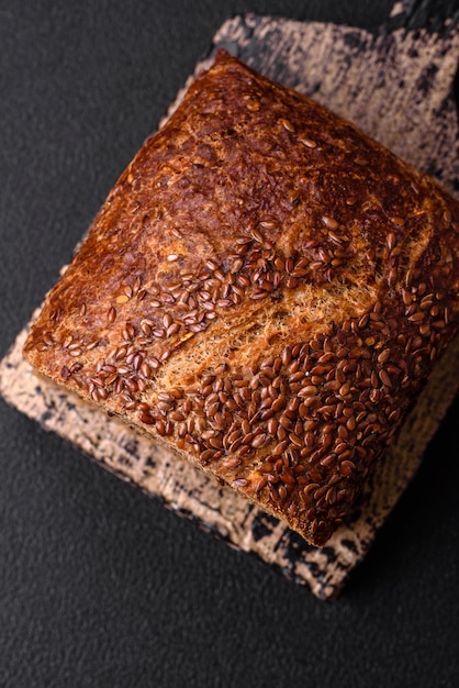 Pyszny, świeży, chrupiący brązowy chleb z ziarnami i nasionami na ciemnym betonowym tle