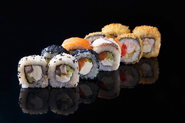 Pyszny zestaw sushi roll z rybą na czarnym tle z refleksji Menu i restauracja