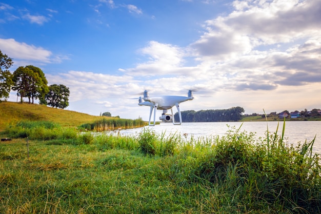 Quadcopter drone latający z kamerą nad jeziorem.