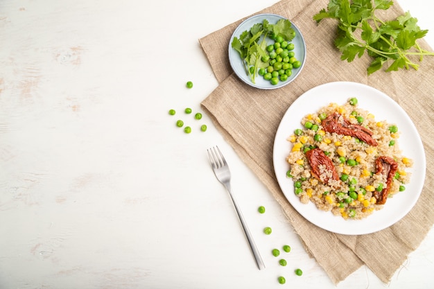 Quinoa Owsianka Z Zielonym Groszkiem, Kukurydzą I Suszonymi Pomidorami Na Ceramicznym Talerzu Na Białym Drewnianym Tle. Widok Z Góry,