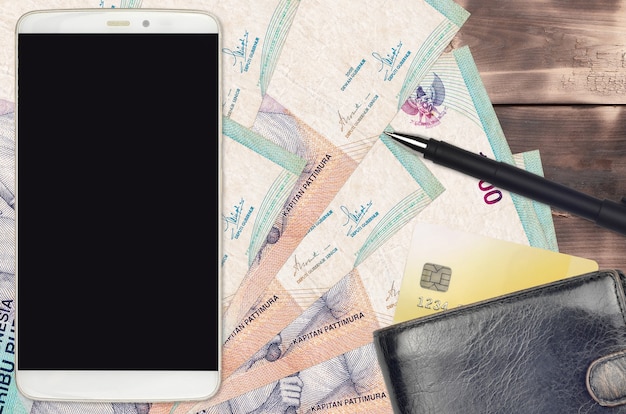 Rachunki za 1000 rupii indonezyjskich oraz smartfon z torebką i kartą kredytową