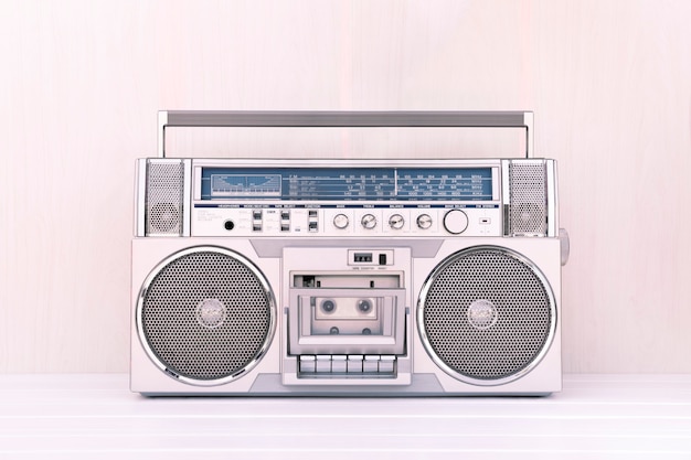 Radio kasetowe retro z lat 80-tych w kolorze srebrnym na jasnym tle drewna. Zagraj w koncepcję muzyki.