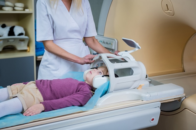 Radiolog przygotowuje dziewczynkę do badania mózgu metodą rezonansu magnetycznego