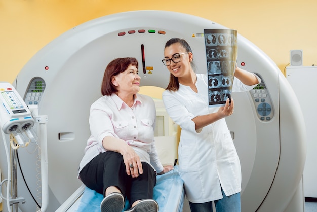Radiolog ze starszą pacjentką, patrząc na zdjęcie rentgenowskie.