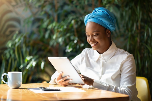 Radosna afrykańska dama doradca biznesowy pracująca online za pomocą cyfrowej klawiatury