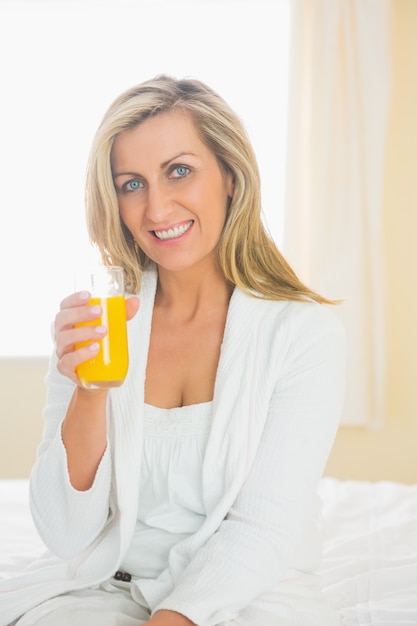 Radosna kobieta patrzeje kamerę cieszy się szkło sok pomarańczowy