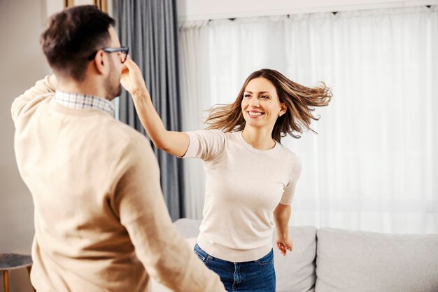 Radosna kobieta tańczy z mężem w ich nowym mieszkaniu