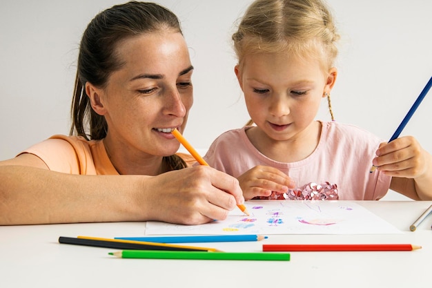 Radosna mama i córka rysują razem kredkami na papierze