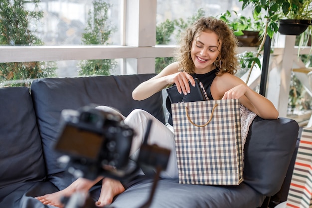 Zdjęcie radosna młoda kobieta blogerka podczas bloga modowego, trzymająca torby po zakupach