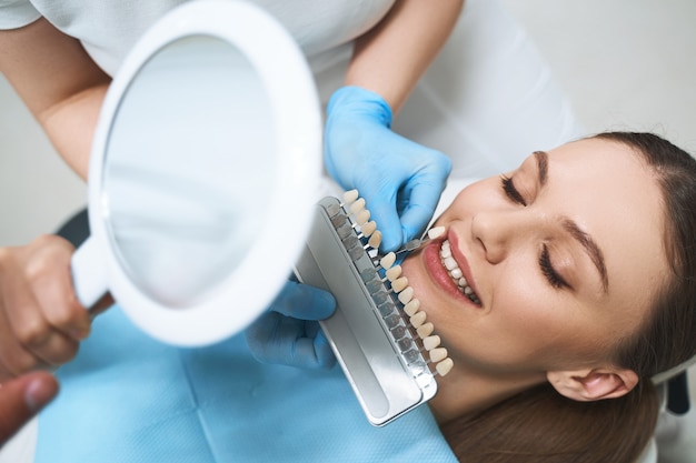 Zdjęcie radosna młoda kobieta odwiedza stomatologa w celu doboru licówek i poprawienia jej uśmiechu pod fachową pomocą